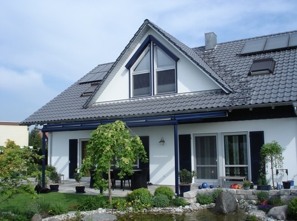 Modernes Einfamilienhaus mit Garten, Solarpanels auf dem Dach und gepflegter Terrasse.