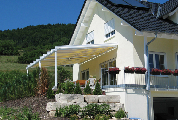 Moderne Terrassenüberdachung aus Aluminium am Einfamilienhaus mit Garten und Markise.